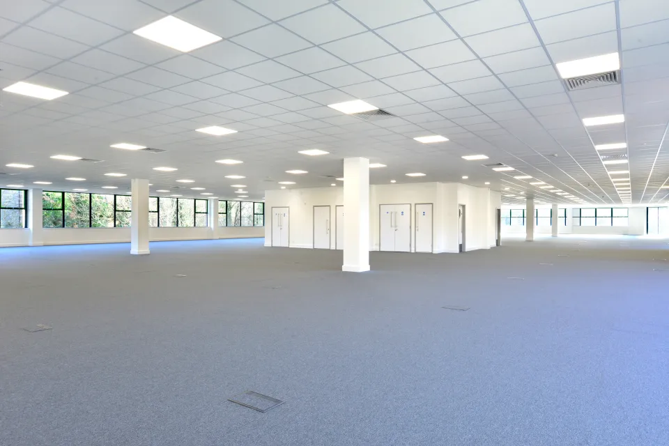 Empty open plan office with gray carpet and white walls
